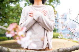 Person wearing loose sweater crosses palms over chest. Face is cropped out