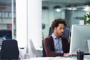 Shot of a young businessman sitting at a desk putting in the hours to get work done