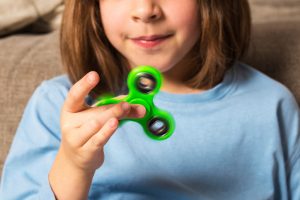 Kid plays with green fidget spinner toy