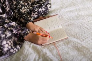 Woman sitting on bed with journal