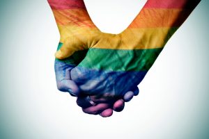 Close-up image of two hands, painted over with rainbow colors