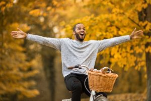 Happy person having fun while cycling with his arms outstretched in autumn day.
