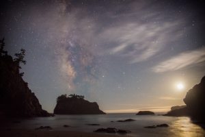 Milky Way and moon at dawn over California beach