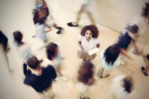 Nervous student standing still in busy private school hallway, blur effect 