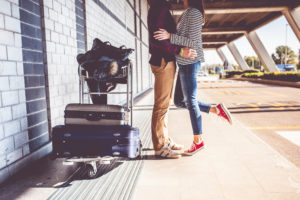 Young couple excited to start trip embraces and kisses on tiptoe outside city