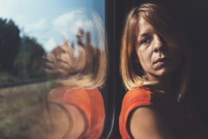 Side view of person with shoulder-length hair looking to the side out window of train