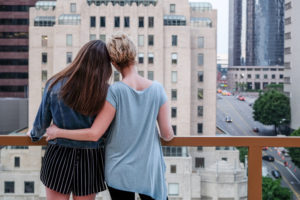 Rear view of mother with arm around daughter's waist on balcony looking over city