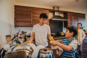 Child helps parents do dishes after meal