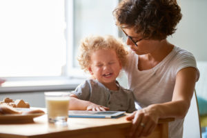 Child cries at dining table while parent attempts to calm child down