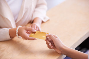 Cropped shot of person with pearl bracelet handing credit card to cashier
