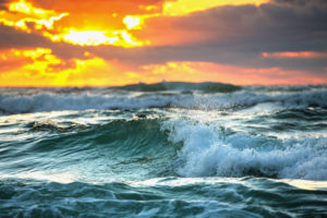 Gentle greenish waves under orange and yellow sunrise