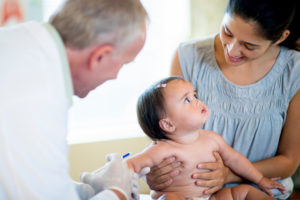 Doctor giving worried baby vaccination