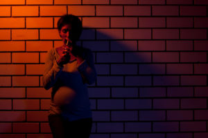 Pregnant woman smoking in an alleyway