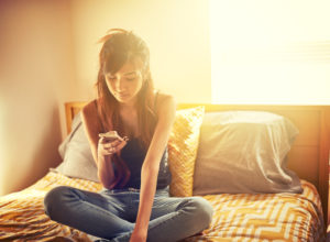 Teenager using smartphone in bedroom
