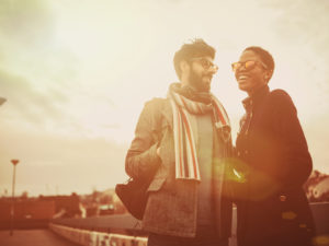 Sepia-toned photo shows couple in autumn clothing standing outside and talking intently with open, happy expressions