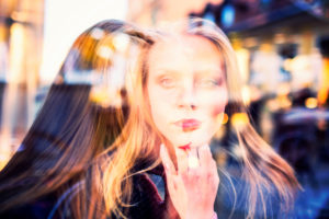 Double exposure image of woman on street in two places at once with long blonde hair, looking out