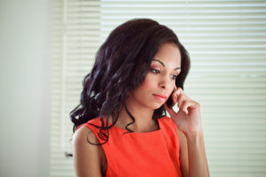 Adult with long curly hair listens on phone with disdain