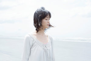 Person with bobbed hair looking out into distance as wind blows hair lightly