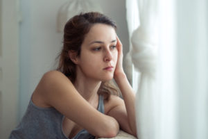 Person at home looking pensive and a bit sad while sitting on sofa