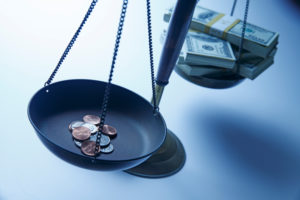 A stack of cash and a stack of pennies on opposite sides of a scale.