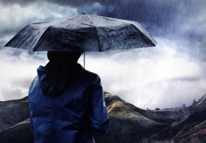 Rear view of person holding umbrella looking out at rain