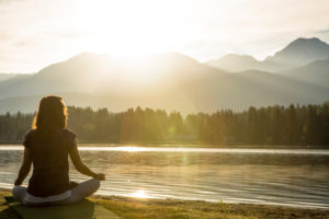 Meditation and yoga practice by lake at sunrise
