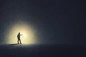 Person holding lamp out ahead walks through dark area