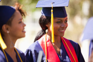 Two graduates at graduation ceremony look happy and proud of their work