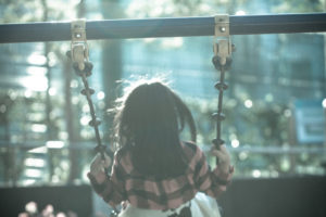 Blurred view photo of back of young girl sitting on swing