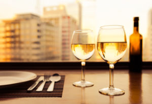 Two glasses of wine next to place setting on table
