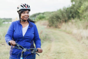 Person in cycling gear wears helmet looking out to the side of frame confidently, ready to ride along hill