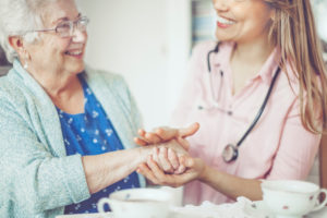 A nurse holds an elderly woman's hand.