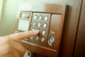 Person's finger pushes button on intercom outside office