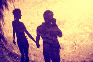 Silhouette of two people holding hands at sunset, rear view photo