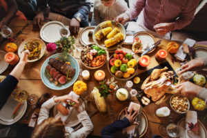 Overhead photo of people seated around table filled with Thanksgiving dishes