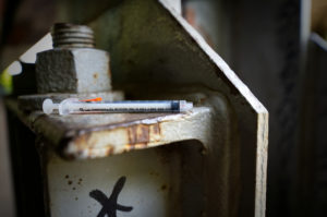 Used heroin syringe found July 2017 between piles of trash at a popular open-air drug camp located under the North Second Street overpass, in the Kensington section of Philadelphia