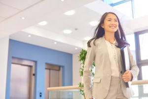 Confident person in suit strides forward out of elevators with pleased expression