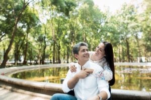 Cheerful mature couple embracing next to pond surrounded by green trees
