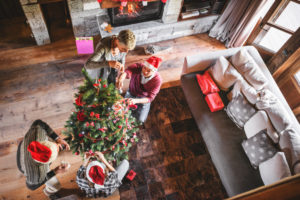 Overhead view of four people standing apart decorating Christmas tree