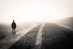 Person walking along road alone during foggy day