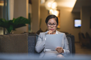 Thoughtful professional reads printed documents in office, pen in hand