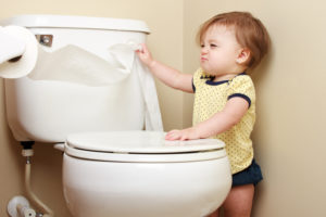 A young girl pulls toilet paper off the roll.