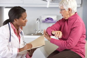 A doctor writes notes as the patient talks about her elbow.