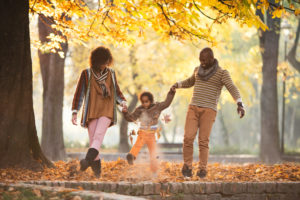 Parents walk in park with child in between, swinging child into air