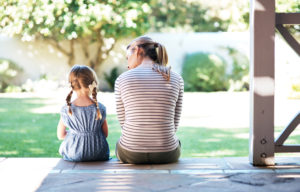 Rear view photo of parent and child sitting on porch having conversation