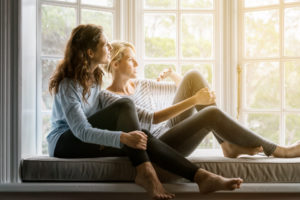 Couple sits together on window seat, deep in conversation, leaning back and looking relaxed