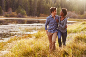 Couple walks through golden field smiling at each other