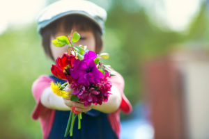 Child holds out small bouquet of flowers