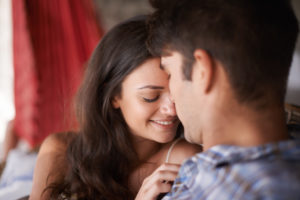 couple sitting on sofa looking at each other intimately and cuddling