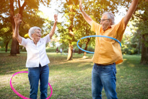 Active senior couple plays hula hoop together in park
